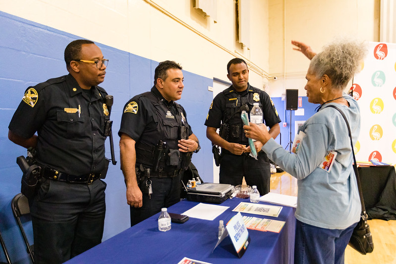 three police officers in uniform, engaging with a citizen telling a story